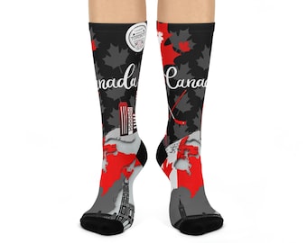 May include: A pair of black socks with a red and white Canadian flag design. The socks feature a hockey stick, maple leaves, and the word "Canada" written in white. The socks also have a small circular logo with the words "Canada" and "Toronto" written in white.