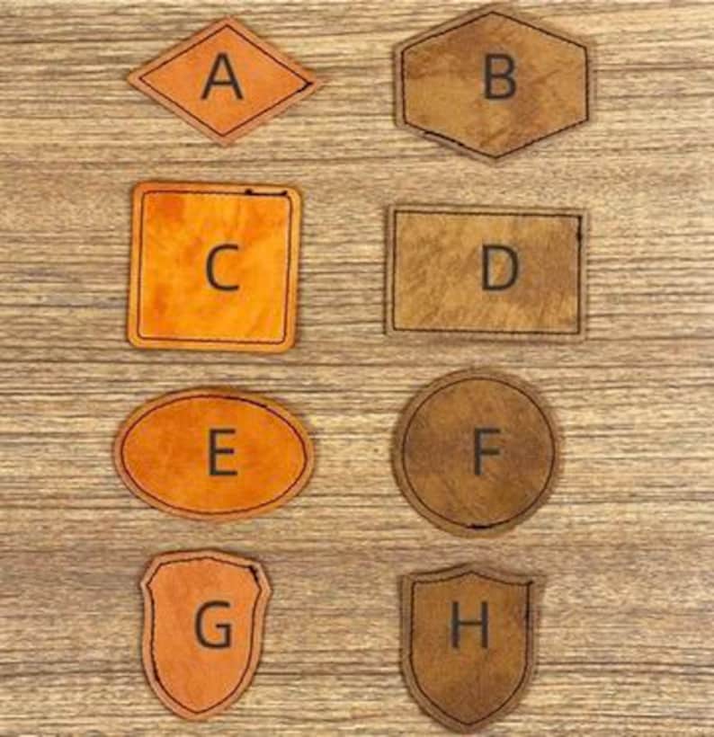 May include: A collection of eight leather patches in various shapes: diamond, hexagon, square, rectangle, oval, circle, shield, and a second shield shape. Each patch features a single letter from A to H.