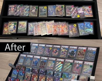 May include: A black display case filled with graded trading cards. The cards are in protective cases, showcasing various colorful designs and characters. The case is open, revealing multiple rows of cards.