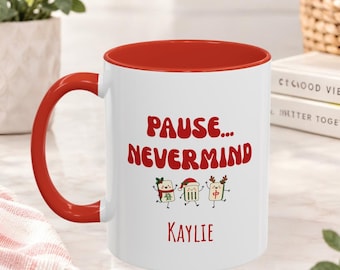 May include: A white ceramic mug with a red interior and handle. The front features the red text "PAUSE... NEVERMIND" above three cartoon mahjong tiles wearing holiday accessories, followed by the name "KAYLIE" in red lettering.