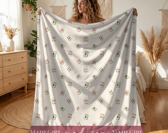 May include: A white fleece blanket featuring a repeating pattern of colorful mahjong tiles. The bottom section includes a wide mauve horizontal band with the white text "MAHJ GIRL madison MAHJ GIRL" printed in a script and sans-serif font.