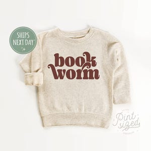 May include: A beige sweatshirt with a brown retro-style graphic that says "book worm".