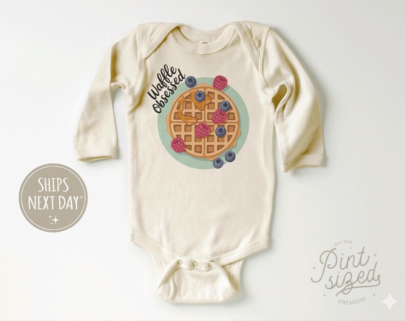 Peut inclure: Body de b&eacute;b&eacute; cr&egrave;me &agrave; manches longues. Le devant pr&eacute;sente un dessin de gaufre avec des myrtilles, des framboises et du sirop, ainsi que le texte "Waffle Obsessed". Une tenue mignonne et confortable pour b&eacute;b&eacute;s.