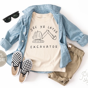 May include: A beige t-shirt with the text "See Ya Later Excavator" and a black excavator graphic, paired with khaki shorts, a denim shirt, and black and white checkered slip-on shoes. Black sunglasses are also included.