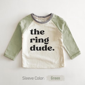 May include: A white long-sleeve shirt with green sleeves. The shirt has a black graphic that says "the ring dude."