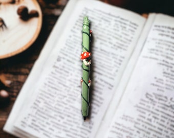 Cute Mushroom polymer clay pen on green clay base with vines.  Includes a ribbon pen cover. Makes a unique gift! Refillable.