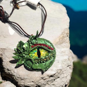 Green Polymer Clay Dragon&#39;s Eye Pendant. Hand sculpted with painted glass cabochon on a 18 in leather cord with organza ribbon.