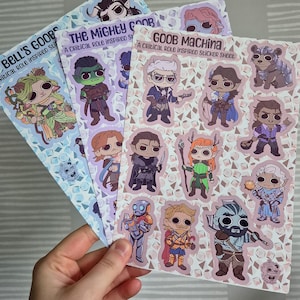 Pode incluir: Três folhas de adesivos com personagens de desenhos animados. As folhas são intituladas "Bell's Goobs", "The Mighty Goob" e "Goob Machina". Cada folha tem uma cor de fundo diferente e apresenta vários adesivos de personagens.