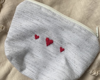 Small beige pouch embroidered with 3 red hearts