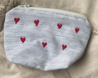 Small beige clutch embroidered with red hearts