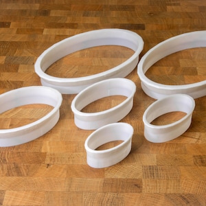 Könnte beinhalten: Satz mit sechs weißen ovalen Ausstechern in verschiedenen Größen.