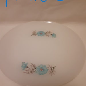 May include: White, round plate with a floral design. The plate features two clusters of blue flowers with gray and brown leaves. The text "plate 3" is written in blue at the top of the image.