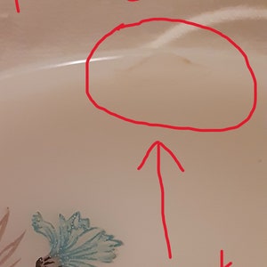 May include: A close-up of a cream-colored plate with a blue floral design. The plate has a crack and the text "plate 4" is written in red.
