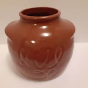 May include: A brown ceramic jar with a rounded shape and a smooth, glossy finish. The jar has a white inscription that reads "Milk 30".