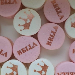 Może przedstawiać: Różowe i białe makaroniki z złotymi koronami i napisem "Bella".