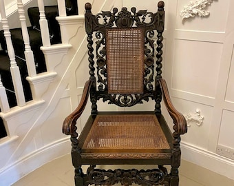 May include: A dark wood carved chair with a cane seat and back. The chair has intricate carvings and a high back.