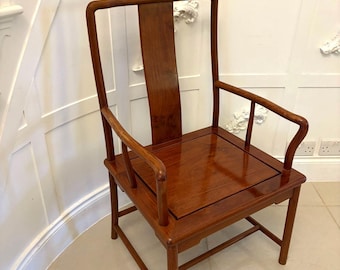 May include: A solid wood armchair with a high back and curved arms. The chair has a dark brown finish and a simple, elegant design.