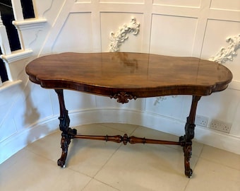 May include: A dark brown antique table with an oval top and ornate carved legs. The table has a glossy finish and decorative carvings along the apron. The legs are intricately carved with detailed designs. The table is approximately 48 inches long.