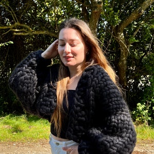 K&ouml;nnte beinhalten: Ein schwarzer, grob gestrickter Cardigan mit langen &Auml;rmeln und einer verk&uuml;rzten L&auml;nge.