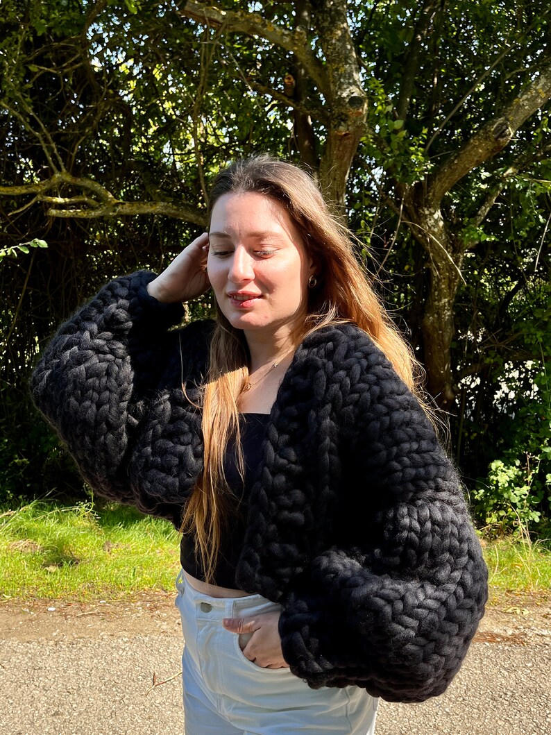 K&ouml;nnte beinhalten: Ein schwarzer, grob gestrickter Cardigan mit langen &Auml;rmeln und einer verk&uuml;rzten L&auml;nge.