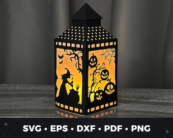 Puede incluir: Una linterna negra con temática de Halloween. La linterna tiene una bruja, murciélagos y calabazas recortadas en el diseño. La linterna está iluminada desde el interior, creando un brillo cálido.