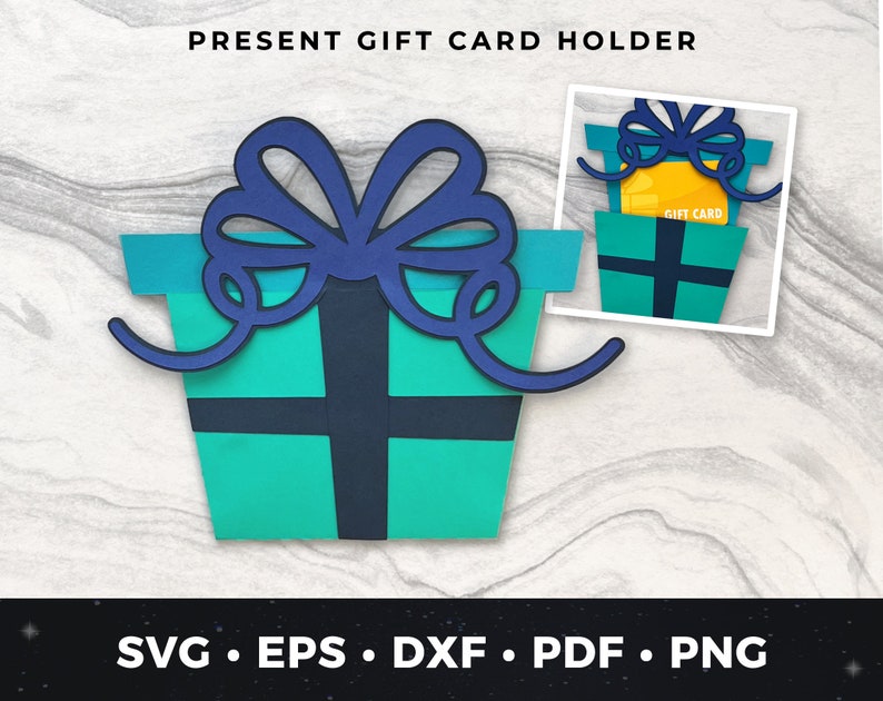 May include: A blue and green papercraft gift card holder shaped like a present box with a blue bow. The holder has a slot for a gift card and the text "Gift Card" is printed on the card.