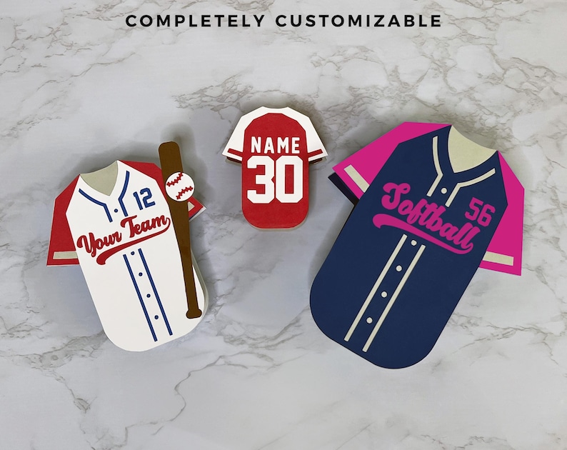 K&ouml;nnte beinhalten: Drei Baseball- und Softball-Dekorationen in Trikotform. Ein wei&szlig;es Trikot mit roten &Auml;rmeln und dem Text "Your Team" und einem Baseballschl&auml;ger. Ein rotes Trikot mit der Nummer 30. Ein marineblaues Trikot mit rosa &Auml;rmeln und dem Wort "Softball".