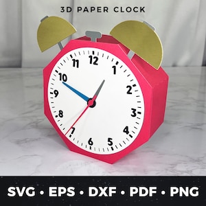May include: A pink 3D paper clock with gold-colored bells and a white clock face. The clock face has black numbers and a blue minute hand, a black hour hand, and a red second hand. The text "3D PAPER CLOCK" is at the top.