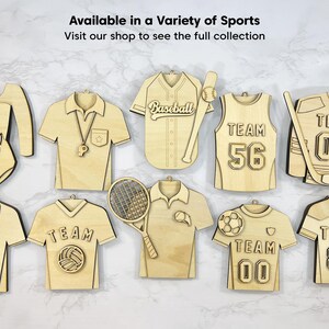 May include: A collection of wooden sports-themed decorations, featuring a gymnastics leotard, baseball jersey, and hockey jersey. The text reads "Available in a Variety of Sports" and "Visit our shop to see the full collection".