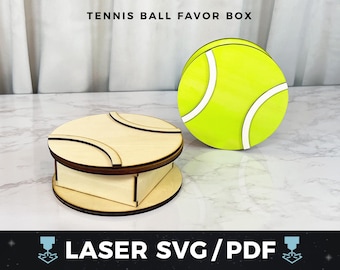 Könnte beinhalten: Eine Tennisball-Geschenkbox aus hellem Holz mit einem passenden Tennisball-Ausschnitt. Die Box ist rund mit einem Deckel mit geschwungenen Linien, und der Tennisball ist leuchtend gelb mit weißen Streifen. Der Text "TENNIS BALL FAVOR BOX" steht oben.