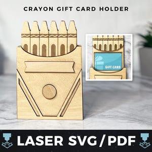 May include: A wooden gift card holder shaped like a box of crayons. The holder has a slot for a gift card and a space for a personalized message. The holder is made of natural wood and has a rustic look. "Gift Card" is printed on the gift card slot.