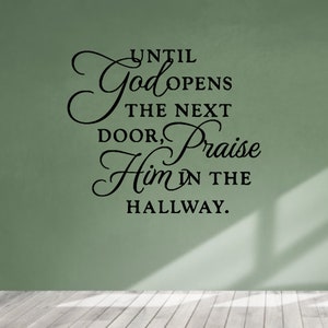 May include: A wall decal with a cursive font that reads "Until God opens the next door, praise Him in the hallway."