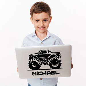 May include: A black and white illustration of a monster truck with the name "MICHAEL" printed below it on a silver laptop.