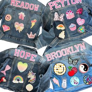 May include: Four denim jackets with different names and colorful patches. The names are Meadow, Peyton, Hope, and Brooklyn. The patches include a rainbow, a unicorn, a mermaid, a butterfly, a cherry, a yin yang symbol, a peace sign, a lightning bolt, a crown, a castle, a cupcake, a heart, a bow, a smiley face, a roller skate, a cat, and a ballerina.