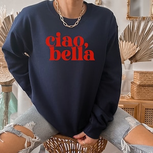 May include: A navy blue sweatshirt with the text "ciao, bella" in red letters.