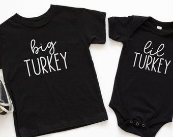 May include: Two black t-shirts with white text. The larger shirt says "big TURKEY" and the smaller shirt says "lil TURKEY".