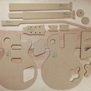 Pode incluir: Um conjunto de modelos de corpo de guitarra de madeira para construir uma guitarra elétrica personalizada. Os modelos são feitos de madeira marrom claro e incluem o corpo, o pescoço, a cabeça e outras partes. Os modelos são etiquetados com o texto "Guitar Body Templates".