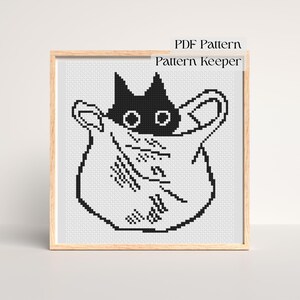 Puede incluir: Patrón de punto de cruz de un gato negro asomando por una bolsa blanca. El gato tiene ojos grandes y redondos y orejas puntiagudas. La bolsa tiene asas y está decorada con líneas cosidas. Las palabras "PDF Pattern" y "Pattern Keeper" están arriba.