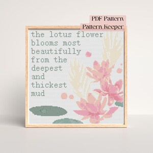 Peut inclure: Une broderie au point de croix encadrée avec le texte "the lotus flower blooms most beautifully from the deepest and thickest mud." Le motif présente des fleurs de lotus roses, des accents beiges et un nénuphar vert.