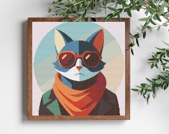 May include: A framed cross-stitch art piece featuring a stylized cat wearing sunglasses and a scarf. The cat has blue and white fur, orange sunglasses, and a red and orange scarf. The artwork is set against a geometric background with a wooden frame.