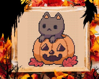 Puede incluir: Punto de cruz con un gato gris dentro de una calabaza naranja tallada. El gato tiene orejas pequeñas y una expresión seria. La calabaza tiene una cara tallada y está rodeada de hojas de otoño, con un marco de madera.