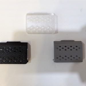 May include: Three small, rectangular, plastic boxes with a patterned design. The boxes are white, black, and gray.