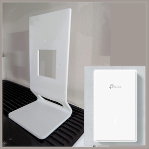May include: White plastic stand for a TP-Link router. The stand has a rectangular opening in the back to allow for the router's power cord and Ethernet cable. The stand is designed to hold the router upright.