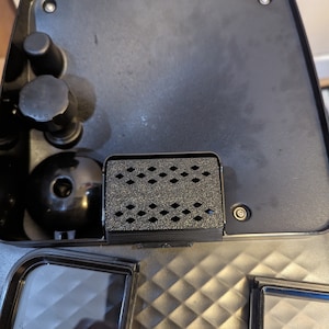 May include: Close-up of the inside of a black coffee machine. The water filter is visible, along with a black water reservoir and a black water tank.