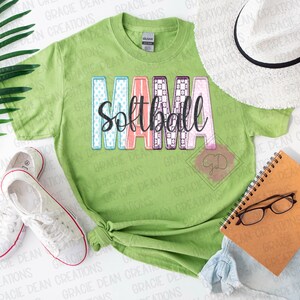 May include: A green t-shirt with the text "Mama Softball" in colorful patchwork letters. The letters are decorated with polka dots, checkered patterns, and floral designs.