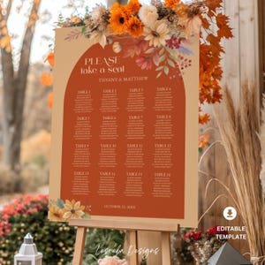 Pode incluir: Um quadro de assentos de casamento rústico em um cavalete, com uma paleta de cores quentes de laranja e bege. A placa diz "PLEASE take a seat" e lista os nomes dos convidados por mesa. Arranjos florais e a data "OCTOBER 22, 20XX" também são exibidos.