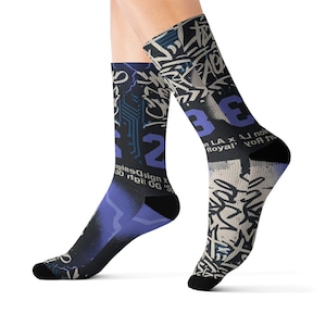 May include: A pair of black socks with a graffiti-style design. The socks feature a mix of white, blue, and black colors, with the numbers "23" and other text incorporated into the design. The socks have black heels and toes.