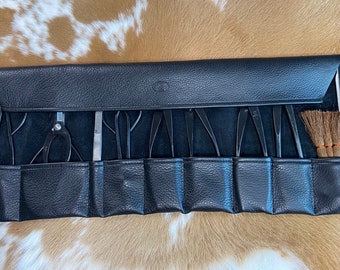 May include: A black leather tool roll with various metal tools, including scissors, tweezers, and picks. A small brush is also included. The tools are arranged in individual pockets within the roll, which is closed with a flap.