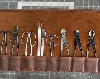 May include: A brown leather roll with 12 slots for holding gardening tools. The tools include pruning shears, a grafting tool, a serrated knife, and a pair of tweezers.