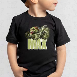 May include: Black t-shirt featuring a monster truck with a zombie driver, lightning bolts, and the name "MAX" in green block letters. The graphic is detailed with green, brown, and gray tones, creating a fun, cartoonish design.